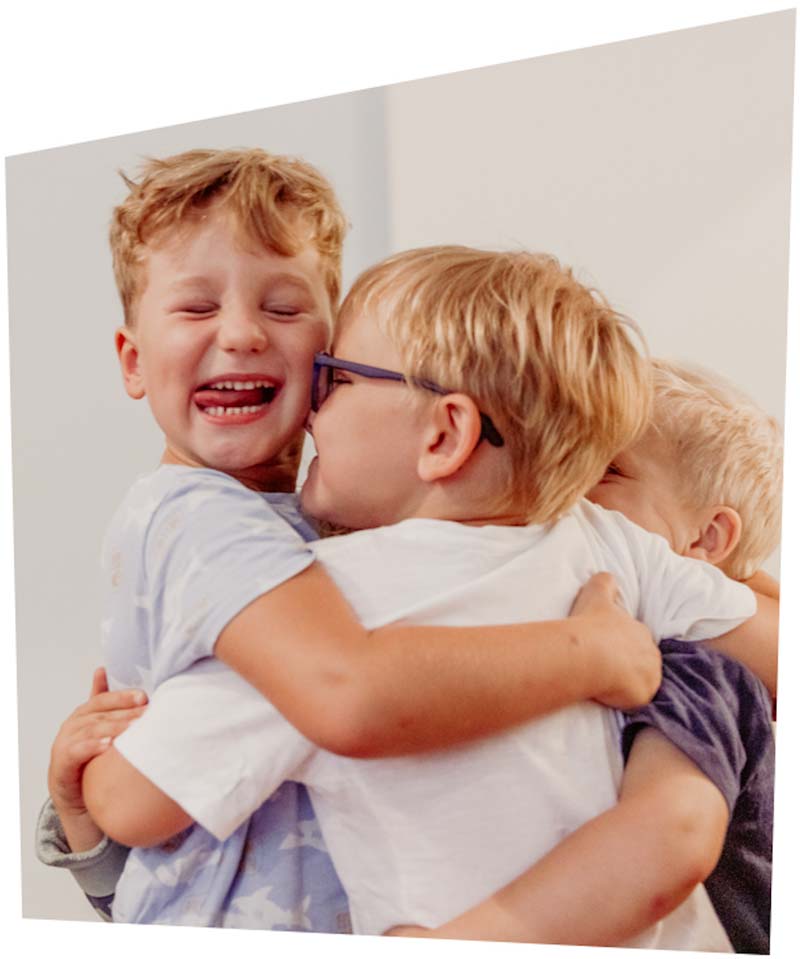 Drei Kinder umarmen sich fröhlich